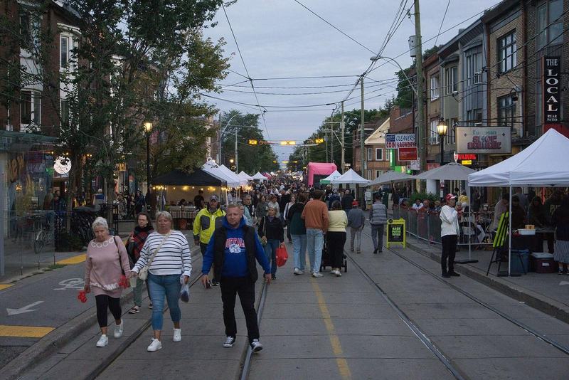 Roncesvalles Avenue during the Roncesvalles Polish Festival, with crowds walking along the streetcar tracks between shops